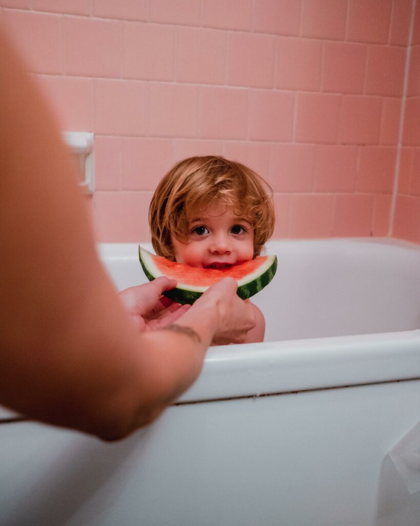 Kind dat watermeloen eet in bad